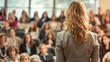 © Alina Tymofieieva - Building view of a young blonde woman in a jacket in front of a business crowd holding a conference. A female speaker leads the event.