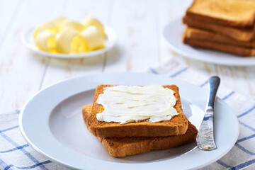 Wall Mural - Butter and crispy pieces of toast for breakfast over white kitchen table, selective focus.