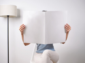 Woman reading mockup of blank newspapers to add your own news isolated on white background.