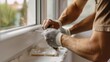© INT888 - Close-up of a Worker's Hand Applying Silicone Sealant to a Window Frame During Home Renovation.