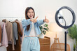 © Katcha - Female online seller is using smartphone to broadcast live on Vlog while making thumbs up for introduce