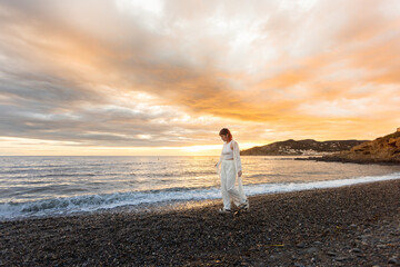 Wall Mural - A woman is walking on a beach at sunset