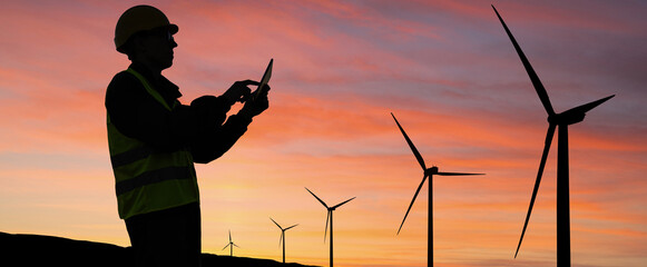 Aufkleber - Engineer with digital tablet works on a field of wind turbines at sunset	