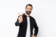 © luismolinero - Young man with beard over isolated white background smiling and showing victory sign