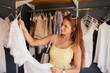 © peopleimages.com - Clothes, retail and shopping with customer woman in store for browsing, choice or outfit selection. Bargain, rack and sale with person in clothing boutique for buying, consumerism or purchase