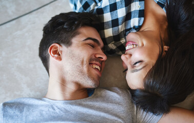 Sticker - Couple, talking and above on floor of home, love and laughing for funny conversation in apartment. Happy people, speaking and laying on ground of living room, support and comedy in relationship