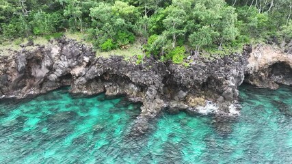 Wall Mural - Seen from the air, a diverse coral reef grows right up to the rugged coastline of a remote limestone island in Indonesia. This scenic, tropical area is part of the Coral Triangle. 