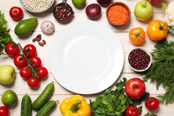 Sticker - Different vegetarian products and plate on light wooden table, top view