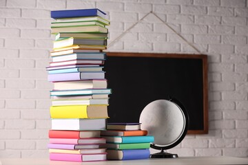 Wall Mural - Stacks of many colorful books and globe on white table in classroom