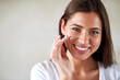 © peopleimages.com - Portrait, woman and sunscreen in home for skincare, dermatology and happy for morning routine. Female person, cream and smile for cosmetics in apartment with glow, shine and moisturizer for facial