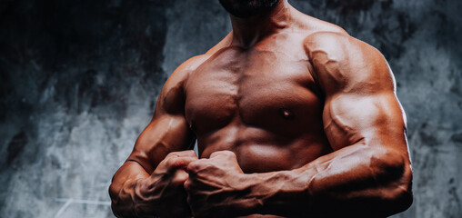 Wall Mural - Young strong man bodybuilder torso on stone wall background