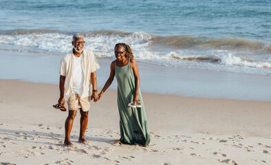 Wall Mural - Elderly black couple enjoying a walk on the beach