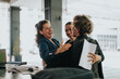 © qunica.com - Group of cheerful business professionals sharing a joyful hug, celebrating success and teamwork in a modern office setting.