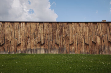 Garden fence with blue sky. Faded wooden fence blue sky background. Old burgundy barn on blue sky background