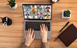 © Prostock-studio - Lady uses a laptop for an online meeting with multiple participants. The laptop is open and the screen shows a grid of video tiles of various people, all in a virtual meeting, top view