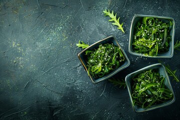 Two square bowls of seaweed salad on dark background