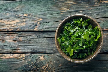 Wall Mural - Wooden table with seaweed salad in bowl flat lay style Room for text