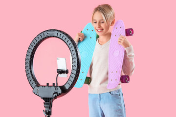 Wall Mural - Teenage blogger with skateboards recording video on pink background