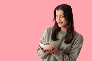 Poster - Young woman with bowl of tasty cereal rings on pink background