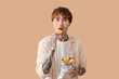 © Pixel-Shot - Shocked young tattooed man eating potato chips on beige background