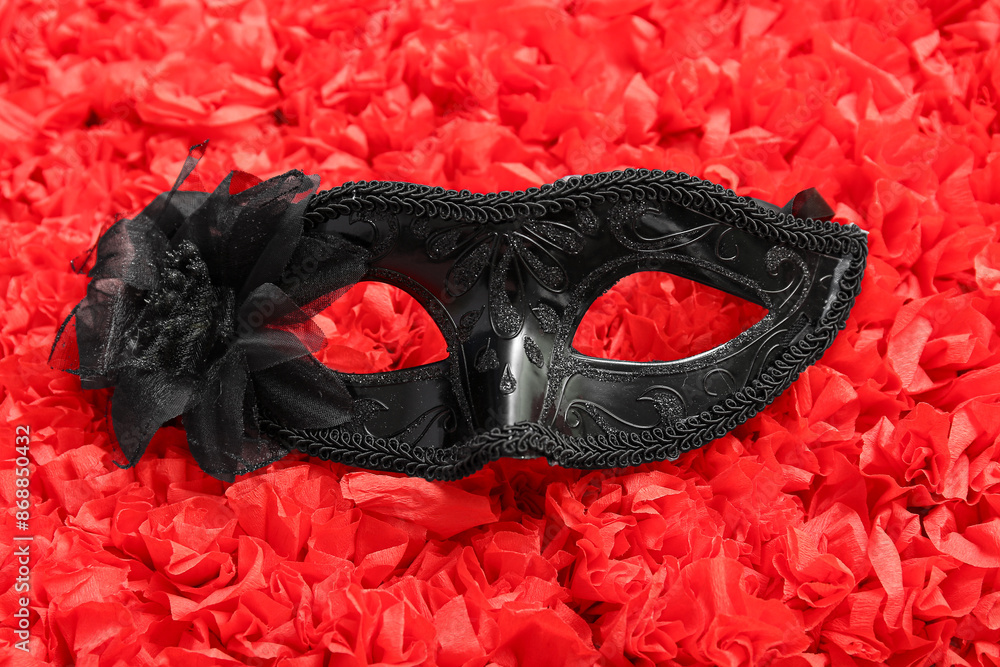 Black carnival mask with flower on red texture background
