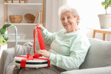 Sticker - Happy senior woman unwrapping robot vacuum cleaner at home