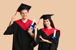 © Pixel-Shot - Happy graduate couple with diplomas on beige background