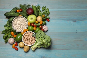 Source of protein for vegetarians. Different fresh vegetables, fruits and cereals on light blue wooden table, top view. Space for text