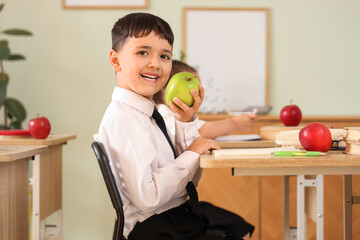 Sticker - Little schoolboy with apple sitting at desk in classroom