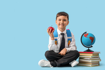 Canvas Print - Little schoolboy with apple, globe and books sitting on blue background