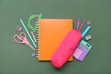 Wall Mural - School supplies with notebook, pencil case and scissors on green background. Top view