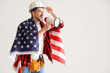 Wall Mural - Male worker with USA flag shouting into megaphone on light background. Labour Day celebration