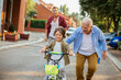 © Geber86 - Father and grandfather teaching young boy to ride a bike on residential street
