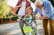 © Geber86 - Father and grandfather teaching young boy to ride a bike on residential street