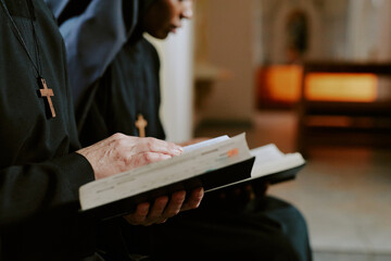 Wall Mural - Selective focus closeup hands of two diverse nuns reading religious texts in books, copy space