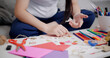 © Johnstocker - Selective focus, Hands of Young Asian woman sitting on sofa decorating a greeting card in the living room, Holiday hobbies, crafts, DIY cards