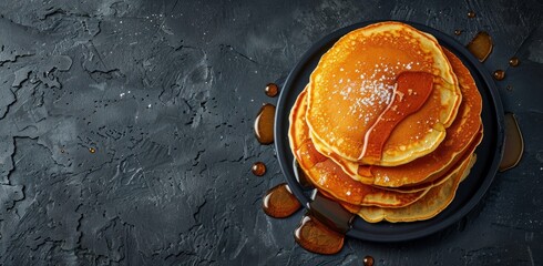 A photo of a stack of fluffy pancakes drizzled with syrup, set against a dark background