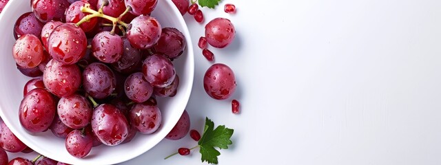 Wall Mural -  A white bowl holds red grapes, nearby sits a leafy parsley sprig on a pristine surface