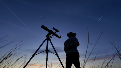 Wall Mural - amateur astronomer looking at the evening skies, observing planets, stars, moon and other celestial 