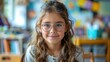 © Алина Бузунова - Caucasian girl with glasses smiling and sitting at desk when reading books at school classroom.