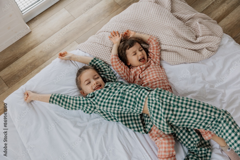 portrait of two girls lying on the bed and posing for a photo after ...