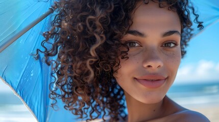 Wall Mural - close up portrait of attractive woman with blue umbrella on the beach, looking at camera and smiling, curly hair, blue sky, cinematic, summer vibes 