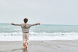 © Westend61 - Woman enjoying sea waves with arms outstretched at beach