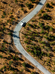 Wall Mural - Aerial view of desert winding road and white car, drone view
