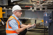 © eakgrungenerd - industrial manager man wearing uniform safety and helmet working with laptop in factory background. industrial man use laptop computer to check electrical system of machine.