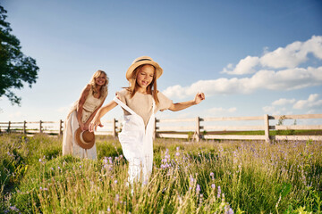 Wall Mural - Running, having fun. Beautiful mother with her daughter on the farm