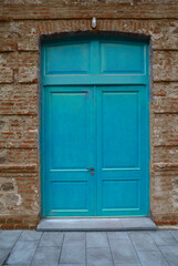 Wall Mural - blue painted Wooden door gate in red brick stone arch. Old, vintage wood arched door in red brick wall. house home vintage retro aged exterior. grey tiled floor. front view. lantern aboму doorway