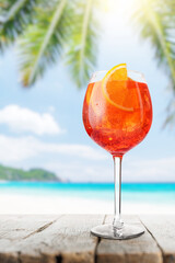 Poster - Glass of Aperol Spritz on a table with a stunning sea and beach background