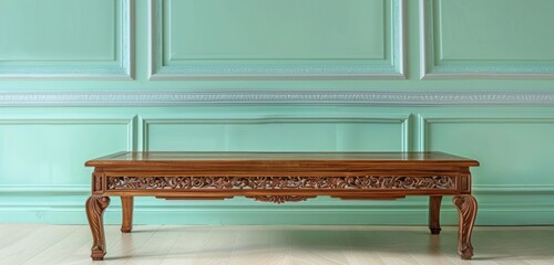 A classic teak wood coffee table with intricate carvings, positioned in front of a light mint green luxury house wall.