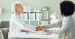 © HockleyM1/peopleimages.com - Mature woman, doctor and handshake with patient for consultation, agreement or checkup at hospital. Female person or medical professional shaking hands with client for meeting, deal or appointment